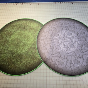 Peut inclure: Deux tapis de jeu ronds, l'un avec une texture de gazon vert et l'autre avec une texture de pierre grise.