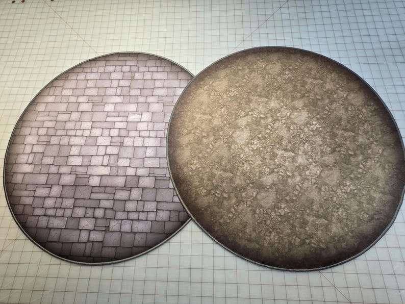 Peut inclure: Deux tapis de jeu ronds, plats et circulaires. Un tapis est de couleur gris clair avec un motif de pierre. L'autre tapis est de couleur marron avec un motif marbr&eacute;.