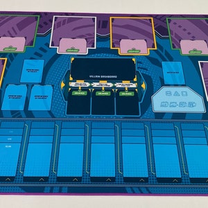 May include: A blue and purple playmat with a grid of card slots and a central area labeled "VILLAIN DISCARD". The playmat is designed for a card game.