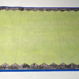 May include: A rectangular game board with a light green hexagonal grid. The board has a blue border and a detailed black and white illustration along the edges. The word "Napoleonics" is faintly visible in the center.