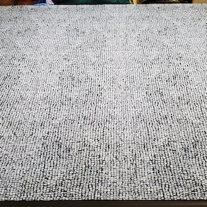 May include: A close-up of a white and black patterned fabric. The fabric has a textured surface and is made of a woven material.