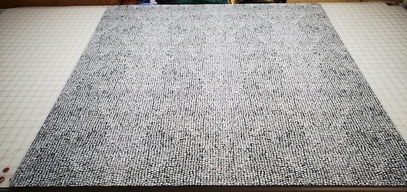 May include: A close-up of a white and black patterned fabric. The fabric has a textured surface and is made of a woven material.