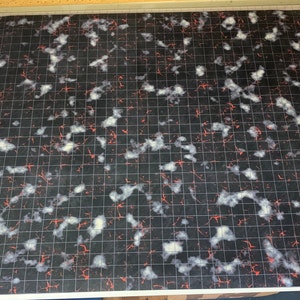 Könnte beinhalten: Schwarz-weißes Spielmatte mit einem Gittermuster und roten Linien. Die Matte hat eine gesprenkelte, marmorierte Optik.