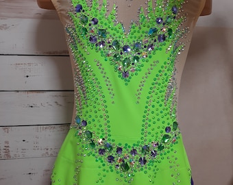 May include: A lime green leotard with a sheer mesh bodice and a skirt. The leotard is decorated with rhinestones in various colors, including green, blue, and silver.