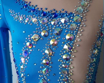May include: A blue leotard with long sleeves and a sheer back panel. The leotard is decorated with iridescent rhinestones in a geometric pattern.