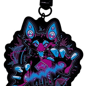 May include: Black keychain featuring a stylized, cartoonish creature with a fox-like face, in shades of black, purple, and blue. The design includes geometric shapes, sound wave patterns, and a heart rate monitor symbol. The keychain has a metal clasp.