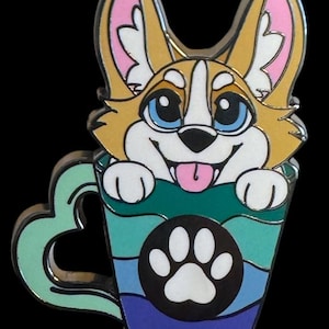 May include: A colorful enamel pin featuring a cartoon corgi dog peeking out of a blue, green, and white striped mug with a paw print on the side. The mug has a heart-shaped handle.