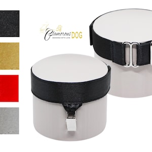 May include: Two white cylindrical containers with black bands and silver buckles. The image also shows swatches of black, gold, red, and silver fabric. The logo "Glamorous Dog" is visible in the upper left corner.