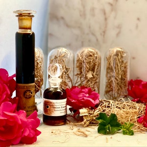 May include: An arrangement of apothecary bottles and vials, containing dark liquids and labeled. The bottles are displayed with red roses and dried plant material. The labels read "Vetiver Essence" and "Vetiveria zizanoides".