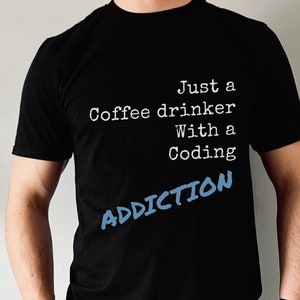May include: A black t-shirt with the text "Just a Coffee drinker with a Coding ADDICTION" in white text with the word "ADDICTION" in blue.