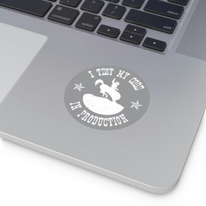 Puede incluir: Una pegatina blanca con fondo gris que muestra a un vaquero montando un caballo salvaje con el texto "I TEST MY CODE IN PRODUCTION" en un círculo con dos estrellas.