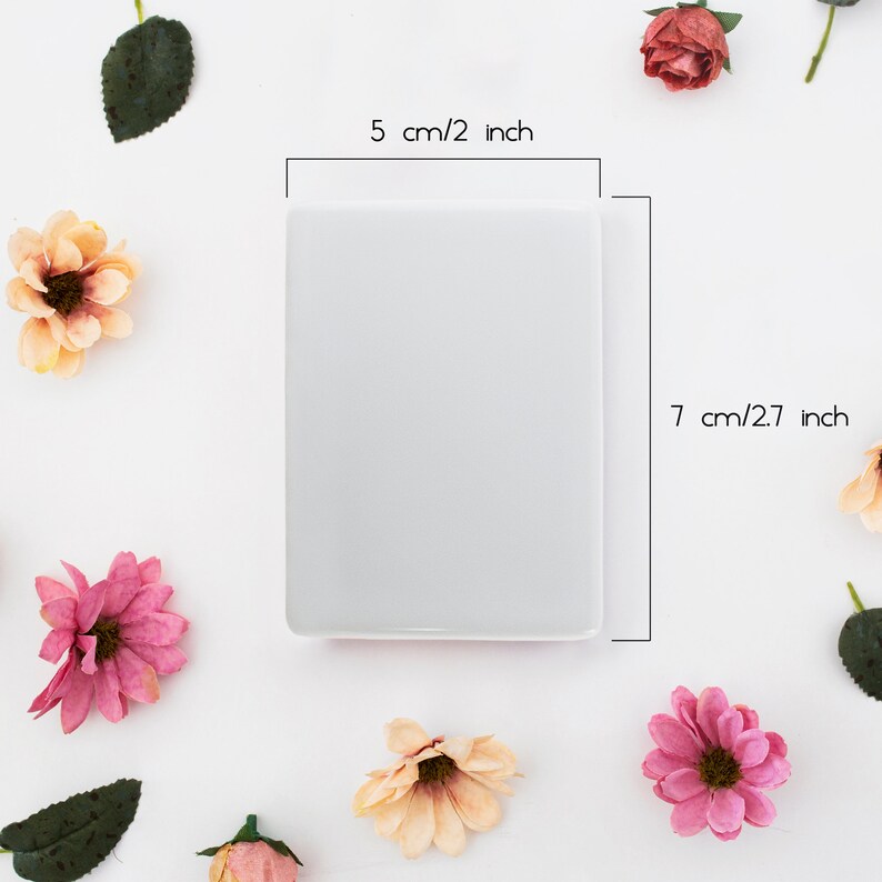 May include: A white blank card with a 2 inch by 2.7 inch measurement. The card is surrounded by pink and peach flowers on a white background.