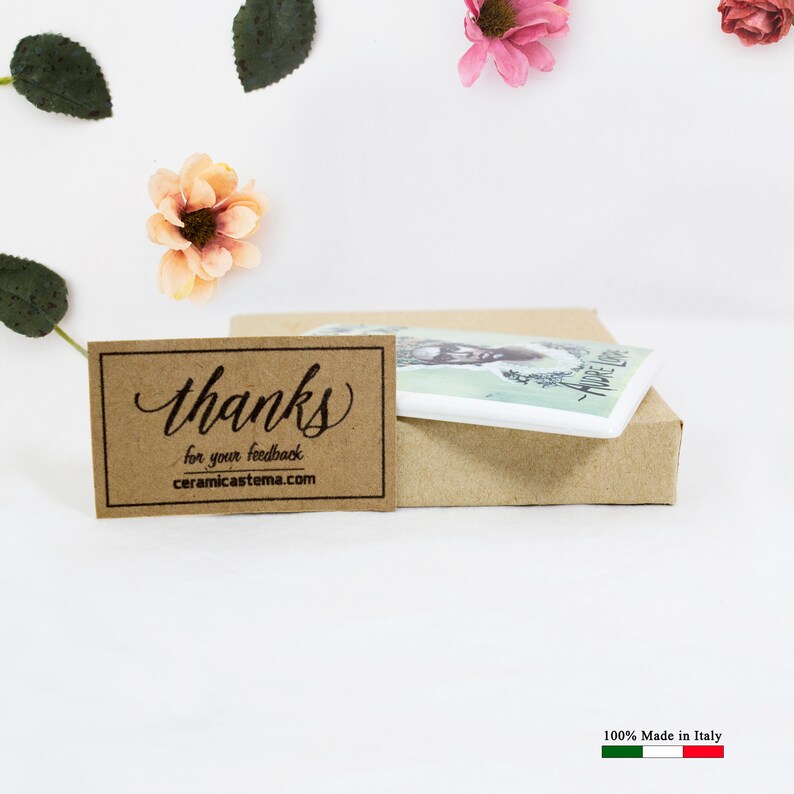 May include: A white ceramic tile with a colorful illustration of a woman's face and the text "Andie Lord". The tile is packaged in a brown box with a thank you note that reads "Thanks for your feedback ceramicastema.com".