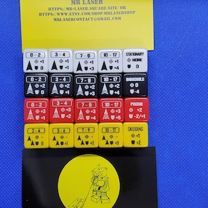 May include: A set of 20 dice with different numbers and symbols. The dice are red, yellow, and black. The dice are used for a game called "MR LASER".