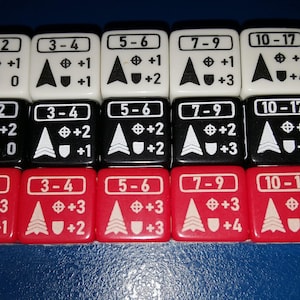 Puede incluir: Un conjunto de 15 dados con diferentes combinaciones de números y símbolos. Los dados son blancos, negros y rojos. Cada dado tiene un rango de números, un signo más y un número. Los dados están dispuestos en tres filas de cinco.