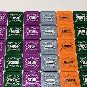May include: A collection of square game tokens with various effects. The tokens are in shades of purple, green, gray, and orange, each with white text indicating game actions like "HEX", "POISON", and "STUN".