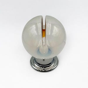 May include: A white glass globe lamp with a chrome base. The globe has a slit in the top and a small light bulb inside.