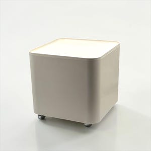 May include: A square, beige storage container with a flat top and rounded corners. The container sits on four small, silver wheels. The design is minimalist and modern, suitable for various storage needs.