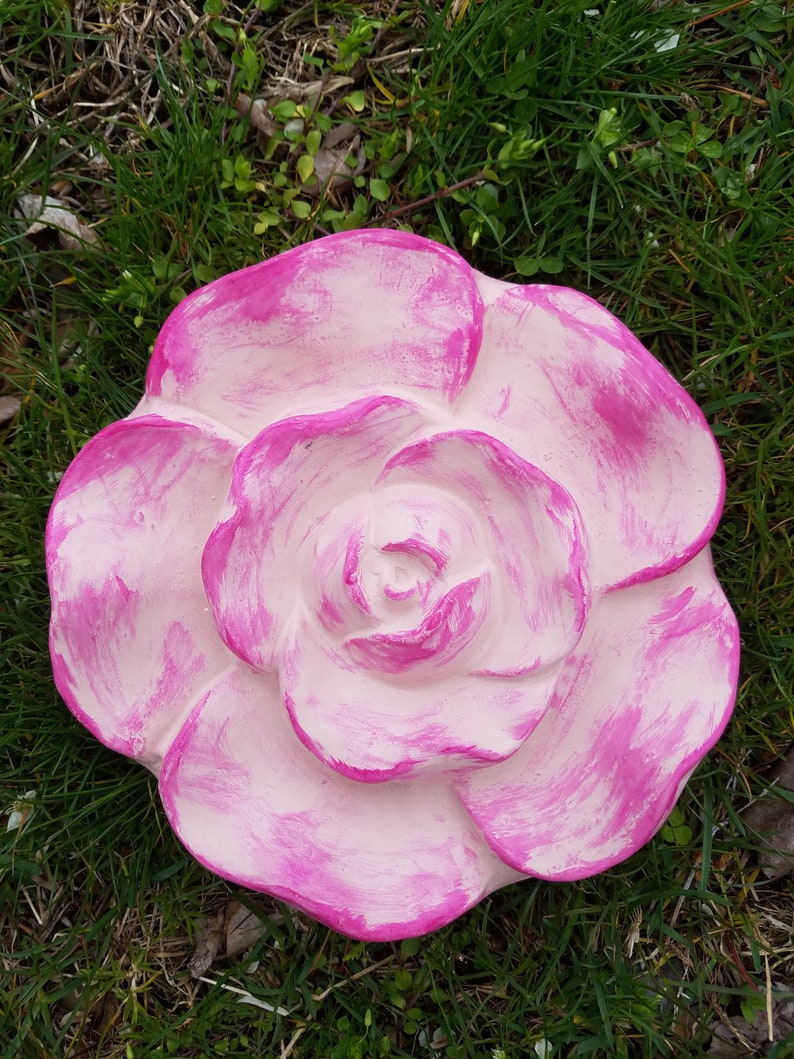 Pu&ograve; includere: Una grande rosa di cemento rosa con una finitura sbiancata e usurata. La rosa &egrave; scolpita con pi&ugrave; strati di petali.
