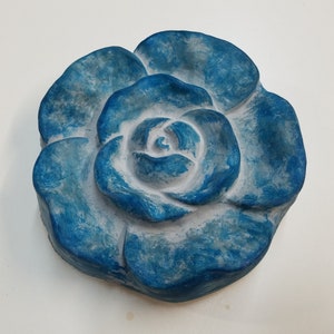 Pu&ograve; includere: Una scultura di rosa in ceramica blu e bianca. La rosa &egrave; dipinta in tonalit&agrave; di blu con un centro bianco.