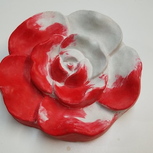 Pu&ograve; includere: Una rosa in ceramica rossa e bianca con una superficie testurizzata. La rosa &egrave; dipinta in uno stile usurato, con la vernice bianca che traspare attraverso la vernice rossa.