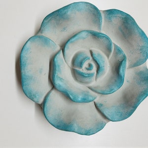 Pu&ograve; includere: Una grande rosa in ceramica bianca con una glassa blu-verde. La rosa &egrave; scolpita con petali dettagliati ed &egrave; un decoro da parete.