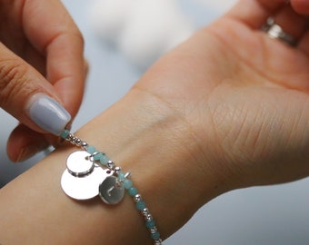 May include: A silver charm bracelet with turquoise beads and two silver charms. The larger charm is round and the smaller charm is a letter L.