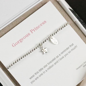 Op de afbeelding: Een zilveren armband met een sterbedel en een klein label met de tekst "Gorgeous Princess". De kaart luidt "wear this little star bracelet as a reminder that you are one in a million and I love you so much!" en "Designed in Scotland, Silver plated".