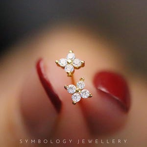 May include: A pair of gold earrings with a four-point star design set with clear cubic zirconia stones.