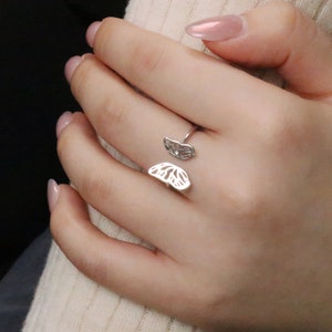 Puede incluir: Un anillo de mariposa de plata con dos alas. El anillo es abierto y ajustable para adaptarse a diferentes tamaños de dedos.
