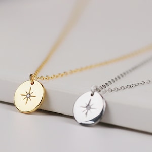 May include: Two delicate necklaces with a round pendant featuring a small star with a single diamond in the centre. One necklace has a gold chain and pendant, the other has a silver chain and pendant.