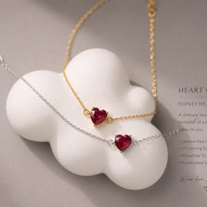 Puede incluir: Dos pulseras delicadas con piedras de granate rojo en forma de corazón. Una pulsera está chapada en oro y la otra es de plata esterlina. El texto en la imagen dice: HEART OF LIGHT, DAINTY HEART BRACELET, Genuine Red Garnet, 925 Sterling Silver / 18K Gold Plated, Adjustable 15.5 - 18.5 cm, Handcrafted with Love, Wear love, share light.