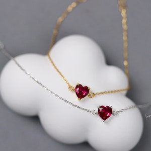 Könnte beinhalten: Zwei zarte Halsketten mit einem roten Herz-Anhänger. Die Halskette links ist silber und die Halskette rechts ist gold. Der Text auf dem Bild lautet "Länge 15,5-18,5 cm Sterling Silber".