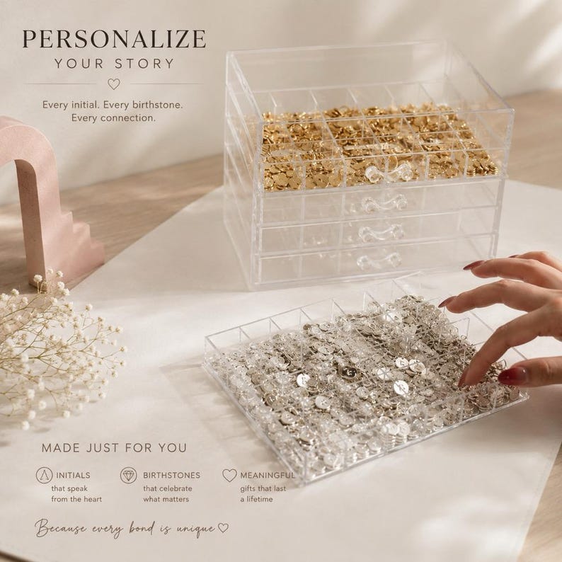 May include: A clear acrylic multi-drawer jewelry organizer containing small gold and silver circular charms. The text on the image reads: PERSONALIZE YOUR STORY, Every initial. Every birthstone. Every connection. MADE JUST FOR YOU.