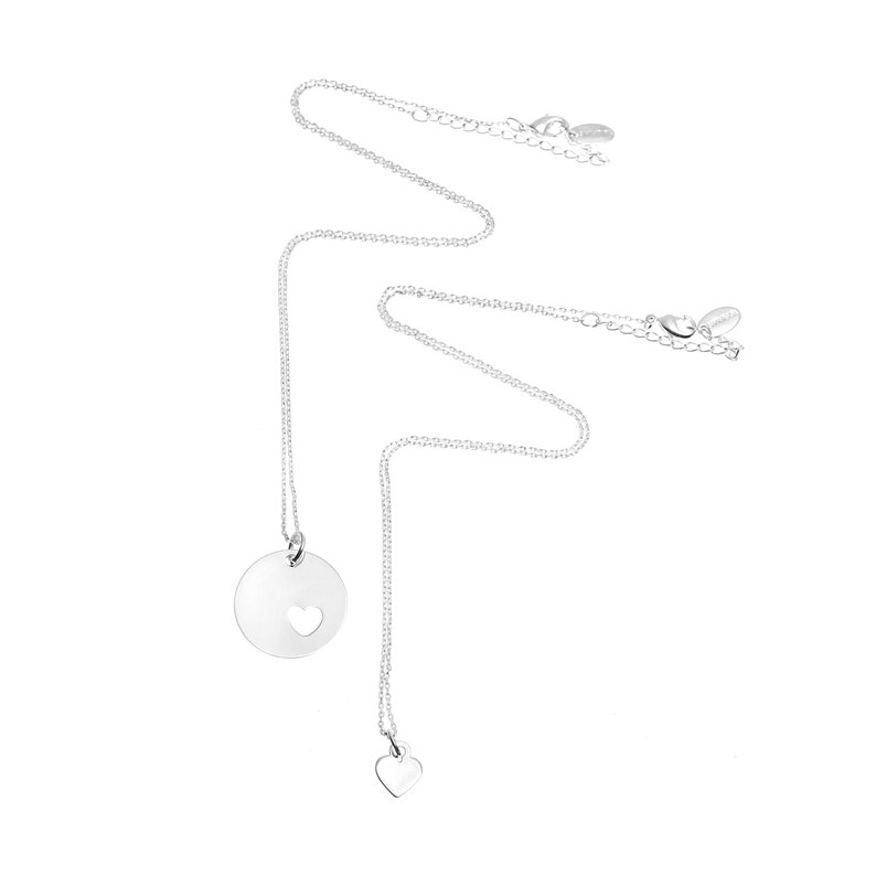 May include: Two silver-toned necklaces with delicate chains. One necklace features a circular pendant with a small heart-shaped cutout. The second necklace has a small, solid heart-shaped charm. Both chains include a lobster clasp and extender.