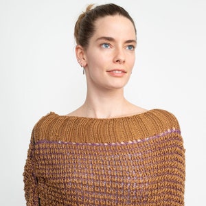 May include: A brown knitted sweater with a purple trim. The sweater has a loose fit and a slightly off-the-shoulder neckline.