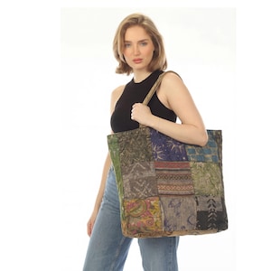 May include: A large rectangular tote bag constructed from various fabric patches in shades of green, blue, brown, and black. The patchwork design features diverse patterns including celestial motifs, geometric shapes, and floral prints with two straps.