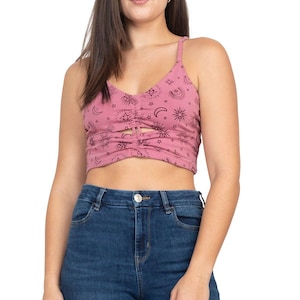 May include: A pink crop top with a celestial print featuring moons, stars, and suns. The top has a cutout detail at the front and thin straps.