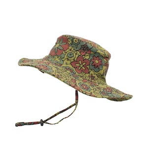 May include: A floral print hat with a wide brim and a chin strap. The hat features a pattern of pink, yellow, and blue flowers on a light green background. The hat is designed to provide sun protection and has an adjustable chin strap.