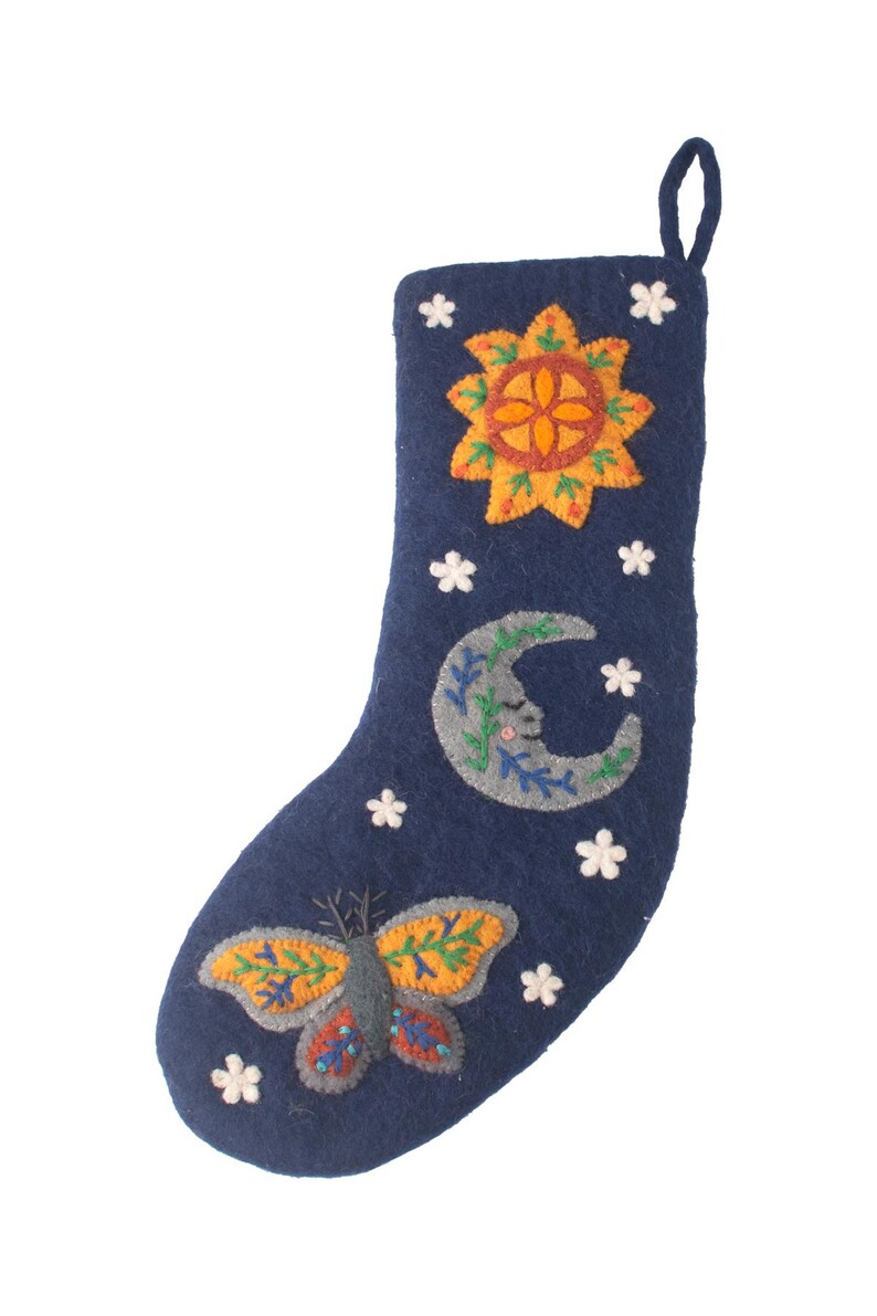Op de afbeelding: Een donkerblauwe vilten kerstkous met geborduurde ontwerpen van een gele zon, een grijze maansikkel met een gezicht en een kleurrijke vlinder. De kous is versierd met kleine witte stervormige accenten en heeft een lus aan de bovenkant.