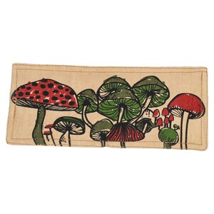 Pu&ograve; includere: Un portafoglio in tessuto beige con una stampa di funghi colorati. I funghi sono rossi, verdi e bianchi con macchie nere.