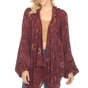 May include: A burgundy hooded cardigan with a celestial print featuring moons, stars, and suns in gold. The cardigan has a draped, asymmetrical hemline and long sleeves.