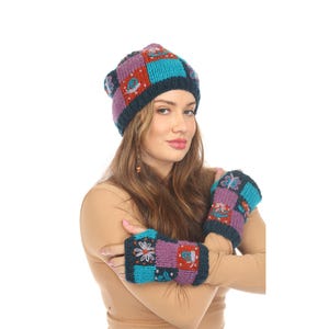 May include: A knitted beanie and matching fingerless gloves featuring a patchwork design in shades of dark blue, purple, and teal. The knit fabric is decorated with embroidered motifs including flowers, butterflies, and snails in contrasting colors.