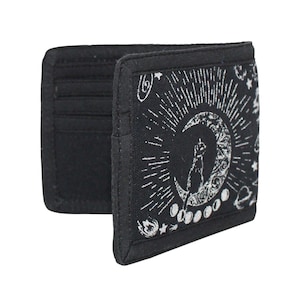 May include: Black wallet with a celestial design. The wallet features a crescent moon with a cat silhouette, surrounded by stars and sun rays. The interior has card slots.