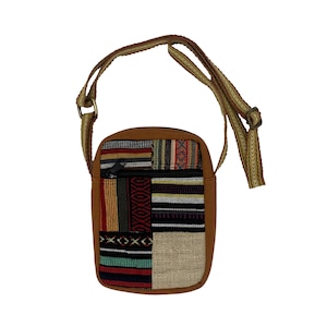 May include: A brown crossbody bag with a patchwork design of colorful woven fabric. The bag has a zippered pocket and a long adjustable strap.