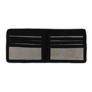 Pu&ograve; includere: Un portafoglio in pelle nera con pi&ugrave; slot per carte e un porta banconote. Il portafoglio &egrave; aperto e l'interno &egrave; rivestito con un tessuto grigio.