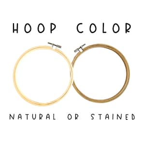 May include: Two wooden embroidery hoops, one natural and one stained, are displayed against a white background. The text "HOOP COLOR" and "NATURAL OR STAINED" are written in black.