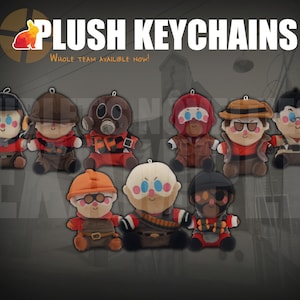 May include: A collection of nine plush keychains featuring various character designs with distinct hats, masks, and accessories. The text PLUSH KEYCHAINS and Whole team availible now! appears at the top above the soft, stuffed figures.