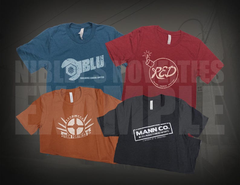 May include: Four short-sleeve t-shirts in blue, red, orange, and black. The blue shirt features a wrench logo and text BLU. The red shirt has a bomb graphic and text RED. The orange shirt displays a circular emblem and Team Fortress 2 text. The black shirt features a rectangular Mann Co. logo.