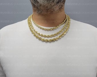 May include: Three gold rope chains of different lengths layered on a person's neck. The chains are made of a thick, twisted rope design.
